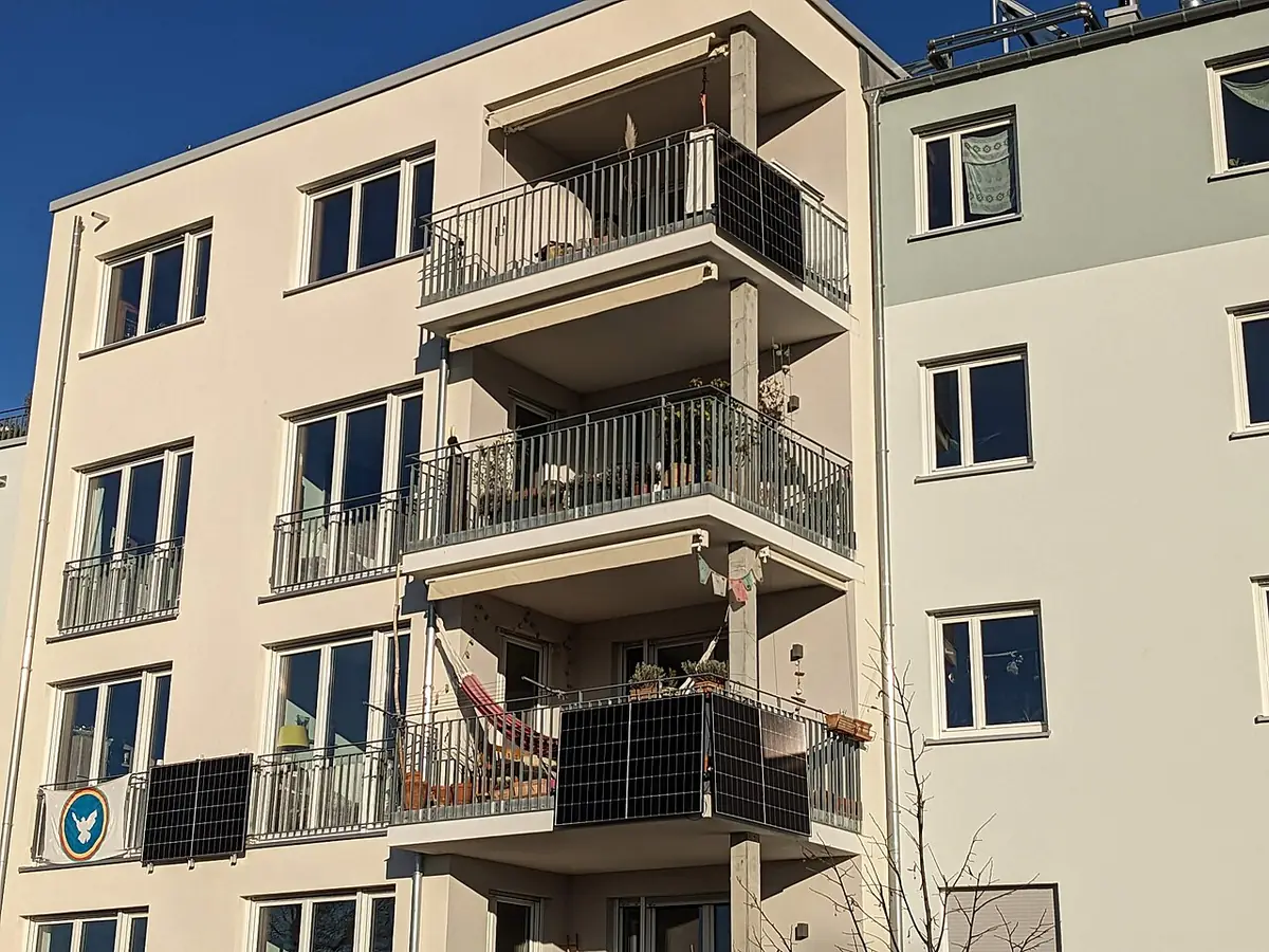 Blok mieszkalny z modułami fotowoltaicznymi typu plug-in przymocowanymi od zewnątrz do balustrad balkonów na dwóch piętrach