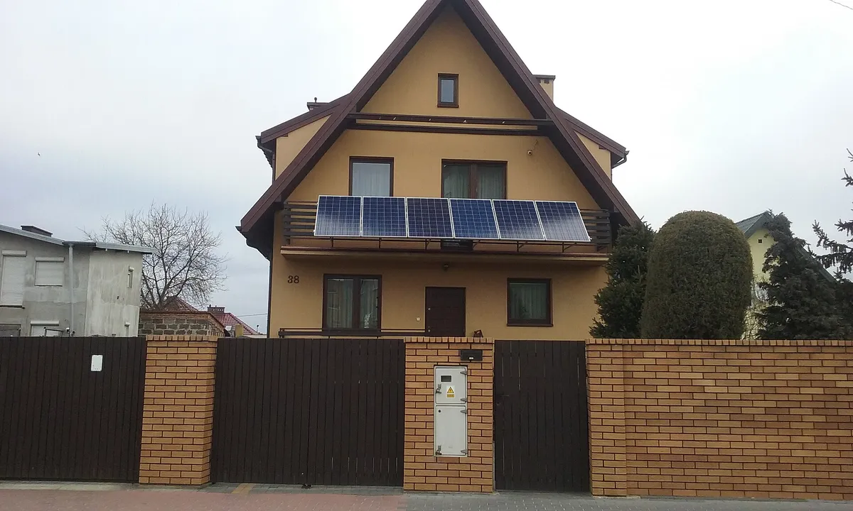 Dom w Tomaszowie Mazowieckim z sześcioma modułami fotowoltaicznymi zamontowanymi na balustradzie balkonu nad wejściem