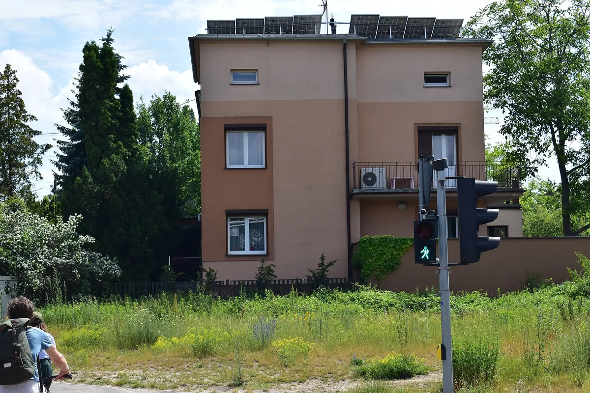 Piętrowy dom w Poznaniu z rzędem modułów fotowoltaicznych na płaskim dachu i jednostką klimatyzacji na balkonie