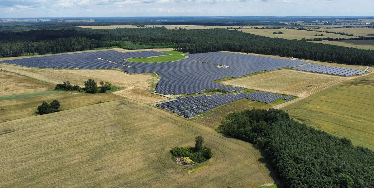 Widok z drona na dużą farmę fotowoltaiczną wśród pól i lasów w pobliżu Chałupczyna