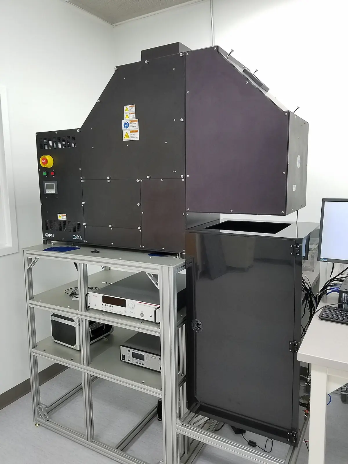 Laboratoryjny symulator słoneczny, duża ciemna obudowa na metalowym stelażu z przyrządami pomiarowymi pod spodem